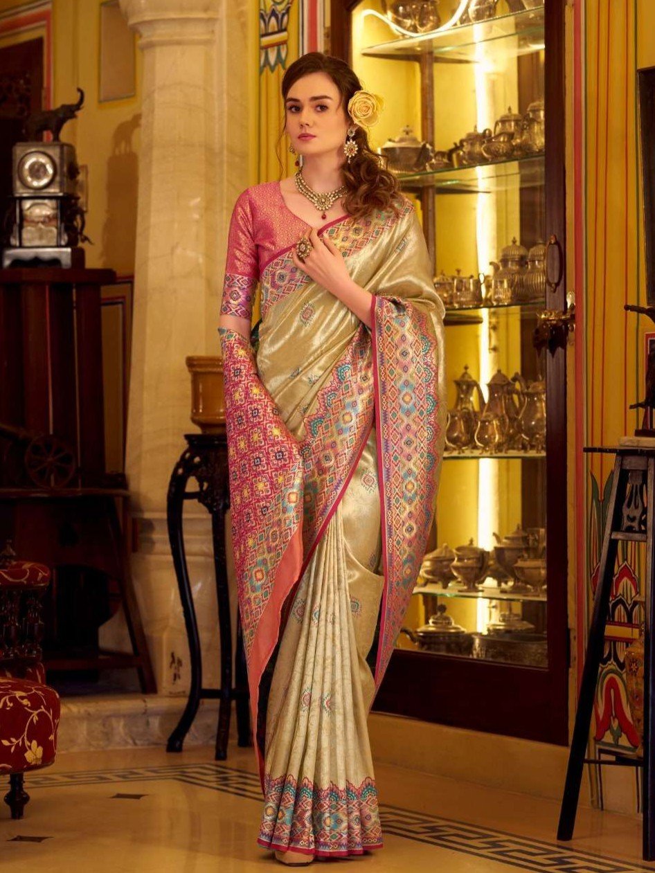 Step into elegance with a beige tissue Patola silk saree and a beautiful blouse piece.